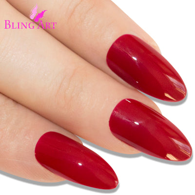 Red polished almond stiletto Bling Art press-on nails — worn-hand close-up showing the crimson high-shine on long pointed almond stiletto tips. Almond = Stiletto (same shape).